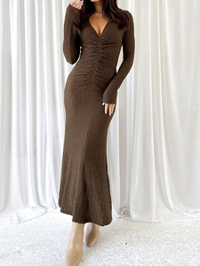 Détail d'une robe en maille marron foncé à col en V montrant le tissu texturé et froncé