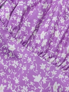 Détail macro des fronces sur le tissu fleuri violet de la robe moulante en soie de lait