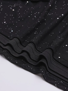 Close-up of black mesh fabric with silver glitter and tiered ruffled hem detail