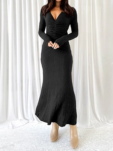 Gros plan sur la robe noire à col en V montrant les détails froncés et le tissu texturé
