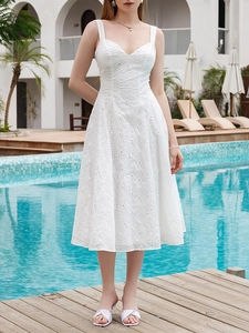 Detailed close-up of intricate white eyelet embroidery and floral patterns on the dress