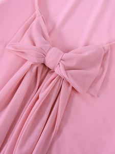 Close-up of pink mesh bow detail on backless dress showing soft tulle fabric texture