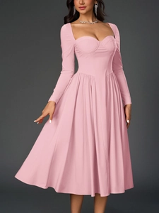 Gros plan d'une robe mi-longue rose à manches longues, décolleté cœur et jupe plissée