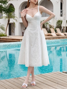 Detail of white V-neck dress featuring delicate floral embroidery and textured cotton fabric