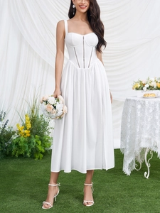 Detail of white corset-style midi dress with slit hem and elegant floral accent