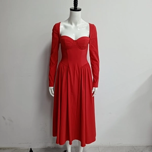Détail d'une robe bustier rouge à manches longues avec col carré et jupe plissée