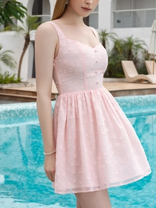 Detail of light pink dress featuring 3D floral embroidery and delicate button accents
