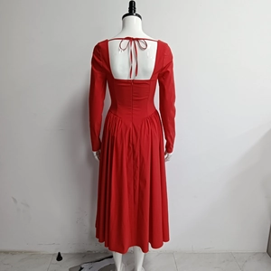 Détail d'une robe rouge à manches longues avec dos nu carré et jupe plissée chic