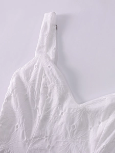 Close-up of white V-neck dress featuring delicate eyelet floral embroidery and thin straps