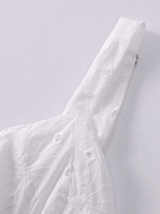 Detail of white jacquard dress featuring intricate eyelet lace and silver metal hardware
