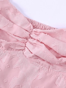 Gros plan d'une robe en maille rose avec jacquard floral et texture smockée élastique