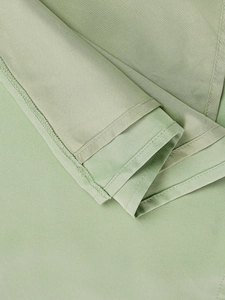 Close-up of sage green fabric showing fine stitching and smooth hem edge detail