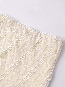 Gros plan du tissu tricot beige avec texture ondulée 3D et broderie de dentelle blanche