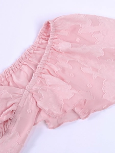 Détail de tissu rose froncé avec jacquard fleuri et bord élastique à volants délicats