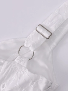 Detail of white jacquard dress with embroidery, metal rings, and adjustable straps