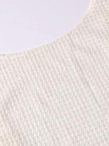 Close-up detail of cream knit fabric texture and neckline on a sexy beach maxi dress