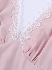 Detail of pink dress featuring a deep V-neckline with delicate white lace trim