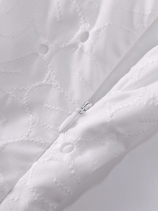 Detailed macro view of white floral eyelet embroidery fabric with hidden back zipper