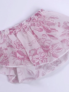 Détail d'une robe en mousseline fleurie rose avec des volants étagés et des bords surjetés blancs