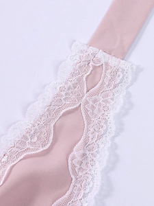 Close-up of pink dress fabric with delicate white lace embroidery and scalloped edges