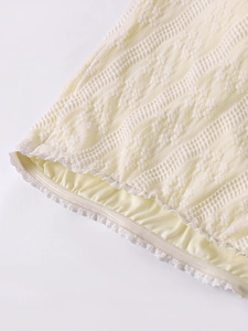 Gros plan sur la maille dentelle crème avec texture florale et ourlet en dentelle cils