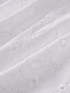 Close-up of white eyelet embroidery and intricate scalloped stitching on lace dress