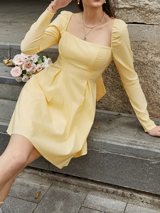 Detail of light yellow mini dress featuring square neckline and puff long sleeves