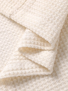 Detailed macro view of cream waffle knit fabric showing premium soft honeycomb texture