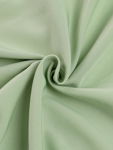 Detail of mint green fishbone dress fabric with soft texture and elegant pleat draping