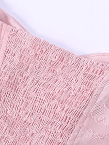 Détail de la robe en maille rose avec smocks élastiques et texture jacquard florale délicate