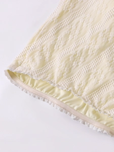 Détail du tissu tricoté jaune clair avec texture 3D et bordure en dentelle blanche