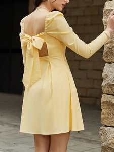 Close-up of the back detail on a yellow dress featuring a large bow and open-back design