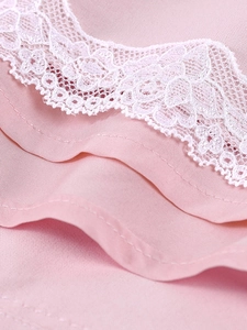 Detailed close-up of pink fabric featuring delicate white floral lace embroidery finish