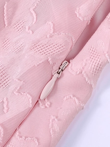 Détail macro de la robe en maille rose avec tissu jacquard floral et fermeture éclair invisible