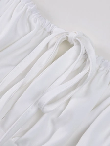 Detail shot of the lace-up drawstring design and white fabric texture on the dress