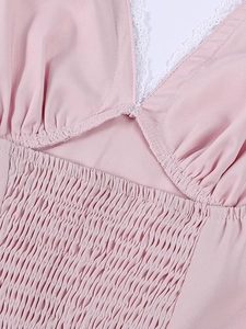 Detail of pink dress featuring white lace trim and intricate smocked fabric texture