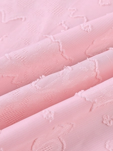Détail du tissu tricoté rose montrant la texture jacquard complexe et les motifs ondulés