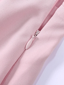 Detail of invisible zipper on light pink woven dress with fine fabric texture