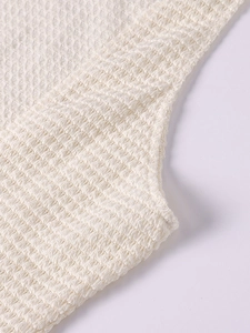Detailed macro shot of cream popcorn textured fabric and fine edge stitching on dress