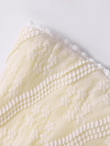 Détail du tissu en maille crème avec motifs jacquard 3D et bordures en dentelle élégantes