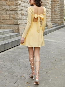 Detail of elegant open back with a large bow on a light yellow long sleeve dress