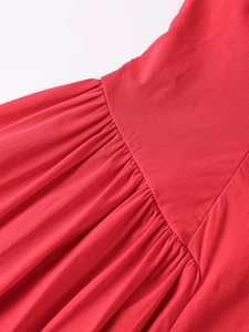 Gros plan détaillé de la taille d'une robe rouge avec plis fins et tissu texturé
