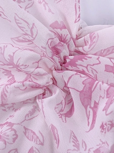 Détail macro de la texture du tissu en mousseline fleurie rose et du drapé de la robe