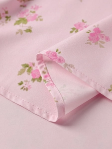 Detail shot of pink floral dress fabric with roses and neat stitching on high-split hem