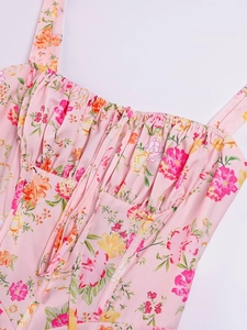 Detail of pink floral dress featuring tie-front bust, ruched fabric, and delicate straps
