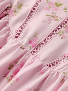 Close-up of pink floral print dress with intricate lace trim and pleated details