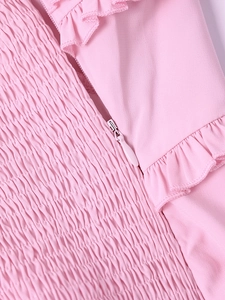 Macro detail of pink chiffon dress featuring smocked fabric and concealed side zipper