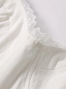 Detail of white Tencel dress featuring delicate lace trim neckline and fine twill texture