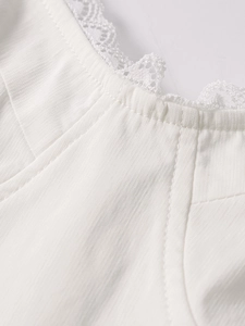 Detail of white rib-knit dress featuring delicate floral lace trim at the neckline