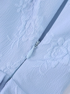 Gros plan sur la texture jacquard bleu clair et le détail du zip invisible assorti